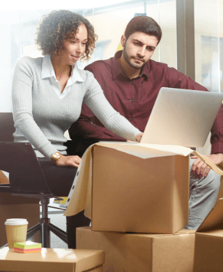 Corporate professionals working as movers move boxes behind them